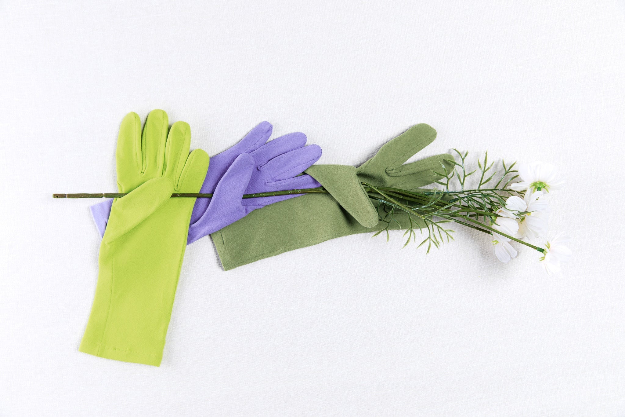Green and purple gloves with a bouquet of flowers on a white background