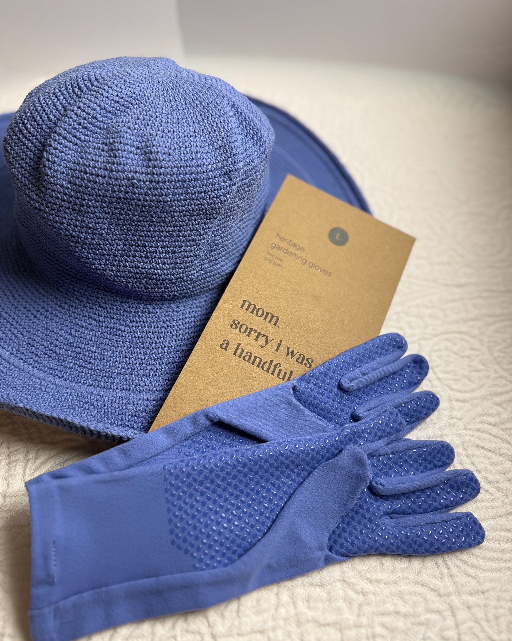 Blue sun hat and matching gloves with kraft packaging on a soft white surface