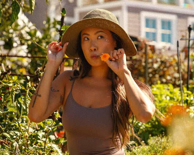 Woman in a garden eating carrots with a house in the background