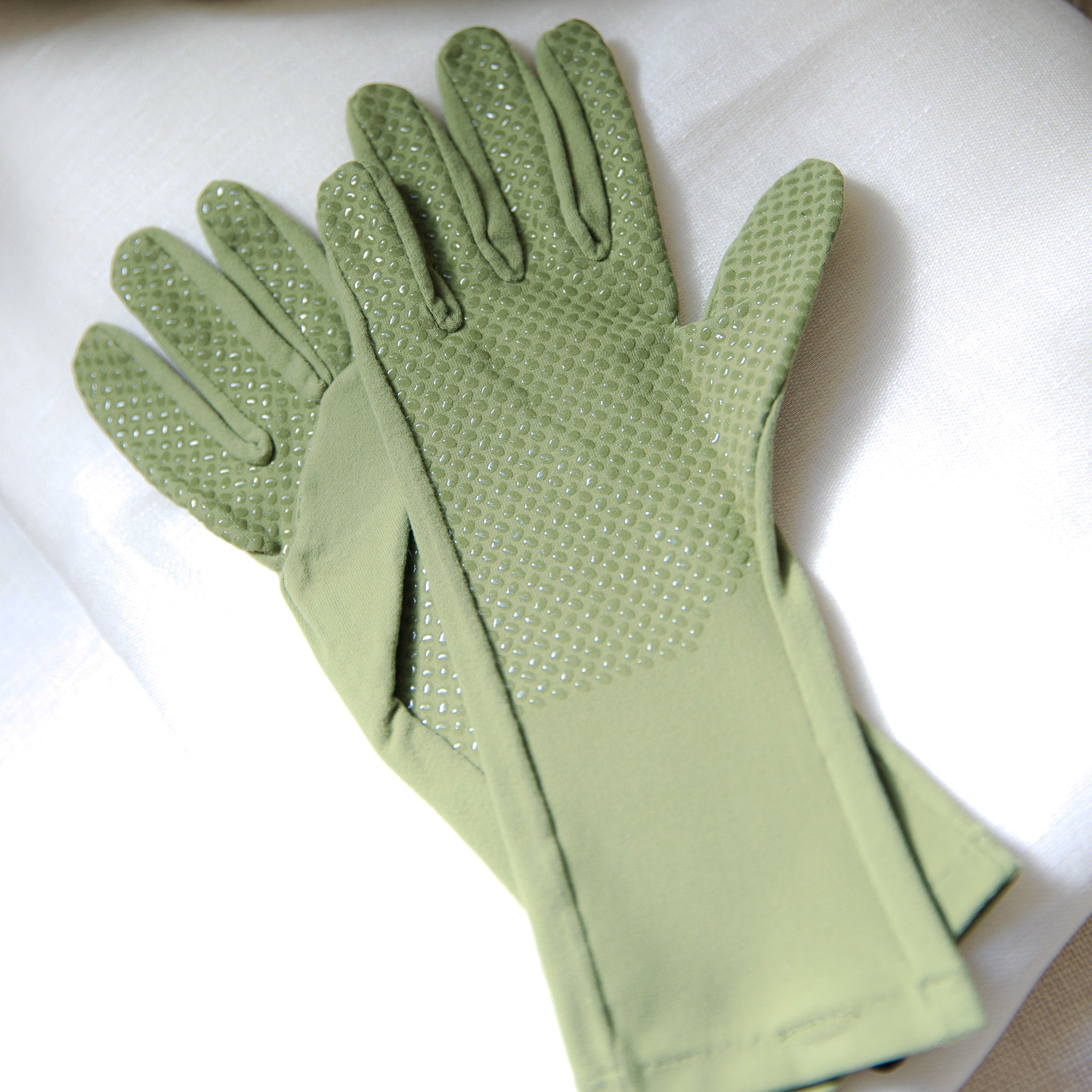 Pair of green womens gardening gloves with grip palm on a white background