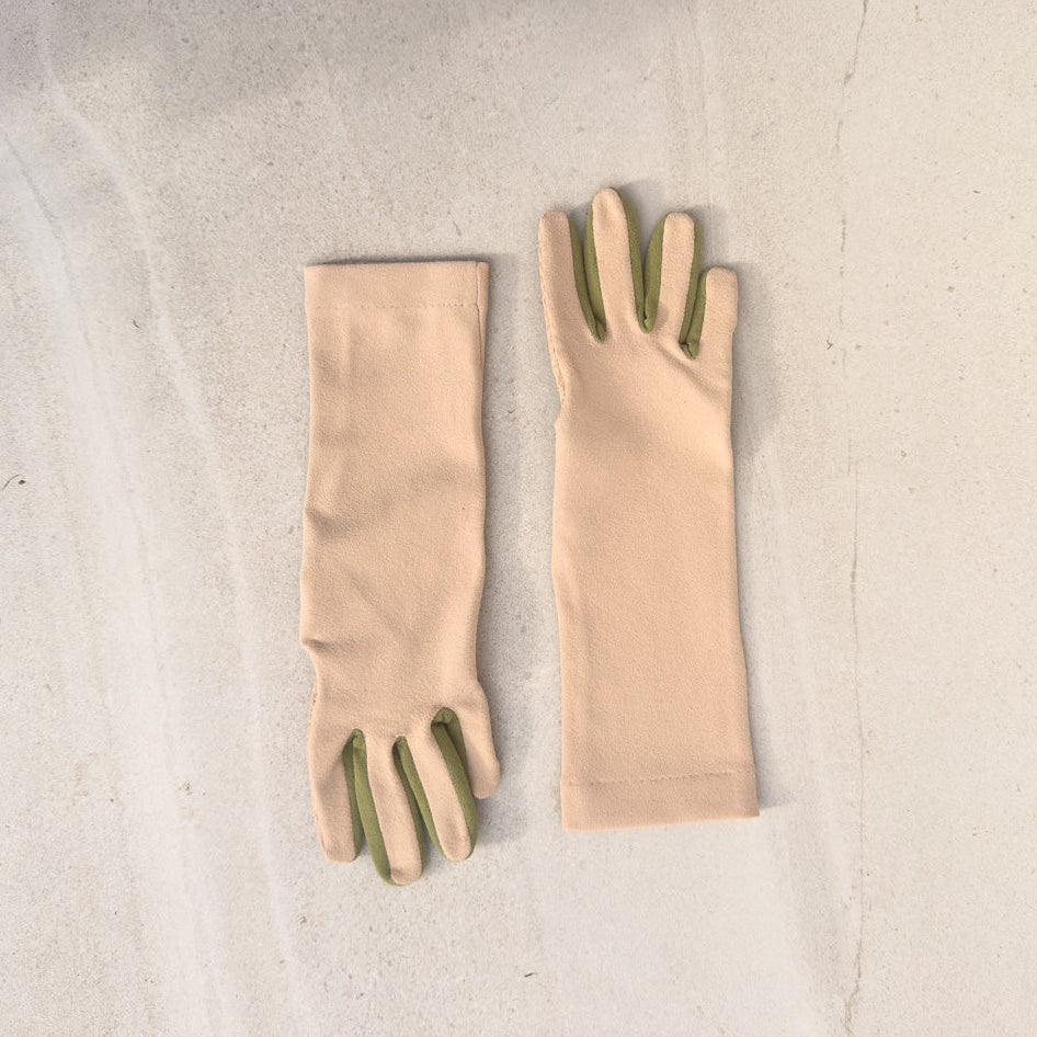 A pair of beige gloves with herb green accents on the fingers, laid flat on a light textured surface.