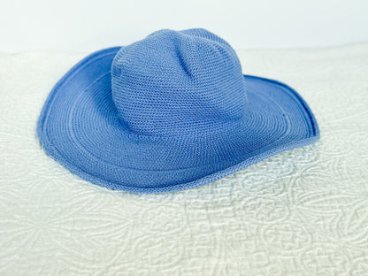 Blue 100% cotton, hand crocheted, sun hat on a soft textured white surface